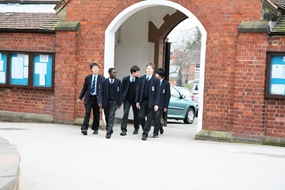 Male secondary students walking through school entrance